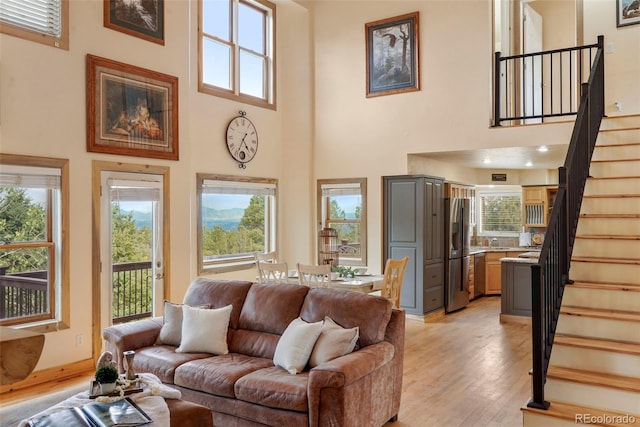 living room featuring a wealth of natural light, light wood-type flooring, and a high ceiling