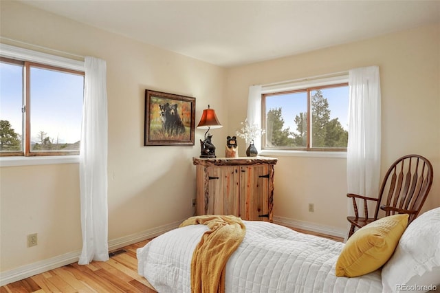 bedroom with light hardwood / wood-style flooring and multiple windows