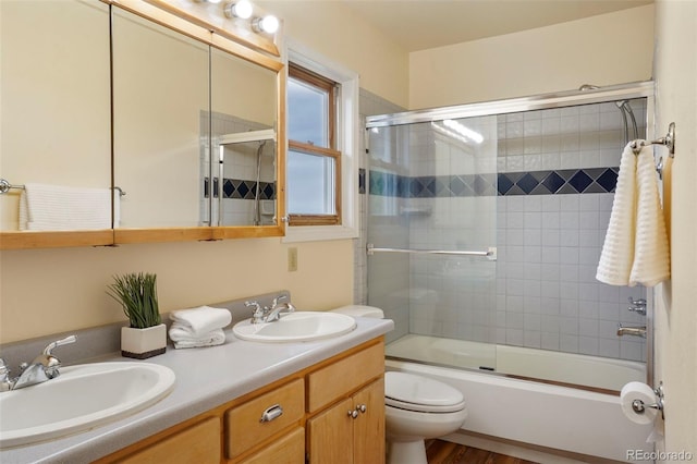 full bathroom featuring enclosed tub / shower combo, toilet, hardwood / wood-style flooring, and vanity