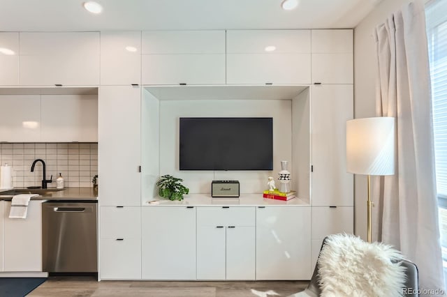 kitchen with a sink, dishwasher, white cabinetry, modern cabinets, and light wood-style floors