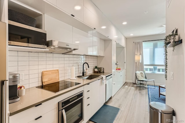 2120 N Downing St Unit 216, Denver, CO 80205 - kitchen with wall oven, white cabinets, black electric stovetop, light wood finished floors, and stainless steel dishwasher