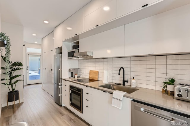 2120 N Downing St Unit 216, Denver, CO 80205 - kitchen featuring appliances with stainless steel finishes, white cabinetry, modern cabinets, light wood finished floors, and decorative backsplash