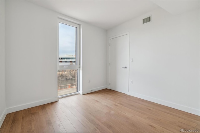 unfurnished room featuring light wood finished floors, baseboards, and visible vents
