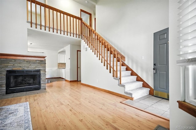 10106 Westside Cir, Littleton, CO 80125 - unfurnished living room with a towering ceiling, wood finished floors, stairway, and a fireplace
