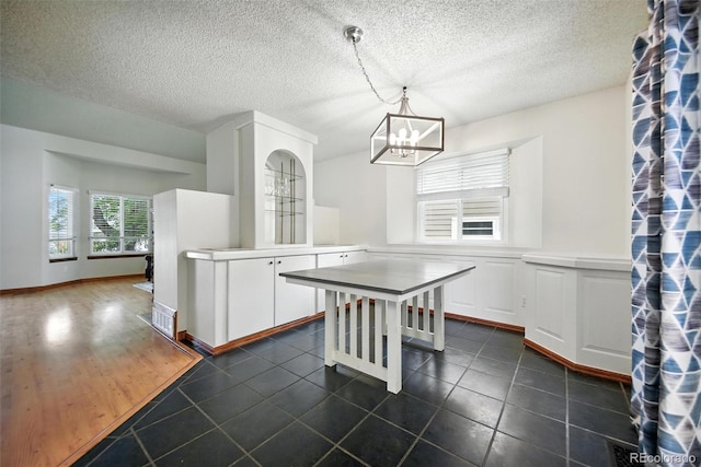 10106 Westside Cir, Littleton, CO 80125 - kitchen with a chandelier, white cabinetry, hanging light fixtures, dark tile patterned floors, and a textured ceiling
