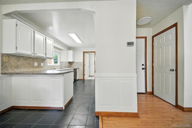 10106 Westside Cir, Littleton, CO 80125 - kitchen with white cabinetry, backsplash, a peninsula, and dishwashing machine