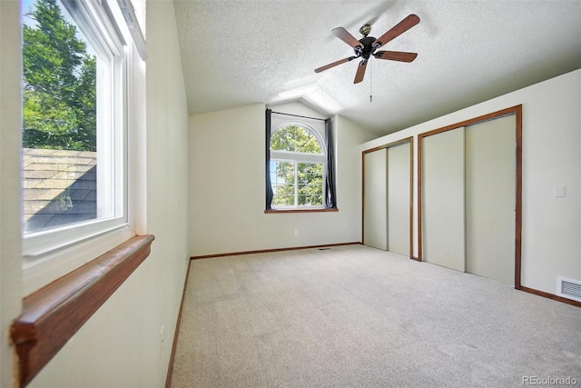 10106 Westside Cir, Littleton, CO 80125 - unfurnished bedroom with two closets, lofted ceiling, a textured ceiling, light carpet, and a ceiling fan