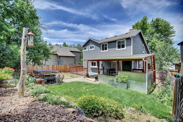 10106 Westside Cir, Littleton, CO 80125 - rear view of house with a chimney, a fenced backyard, a trampoline, and a patio area