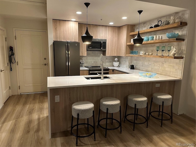 kitchen with freestanding refrigerator, stainless steel microwave, modern cabinets, light countertops, and a peninsula