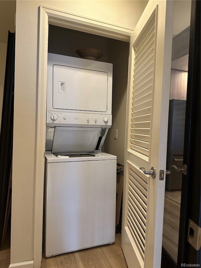 clothes washing area with stacked washer / drying machine and light wood finished floors
