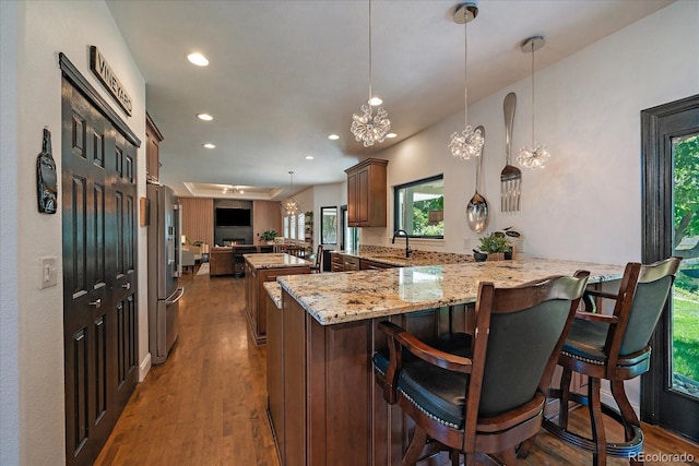 10701 Flagler Dr, Parker, CO 80134 - kitchen with stainless steel fridge with ice dispenser, a peninsula, wood finished floors, light stone counters, and recessed lighting