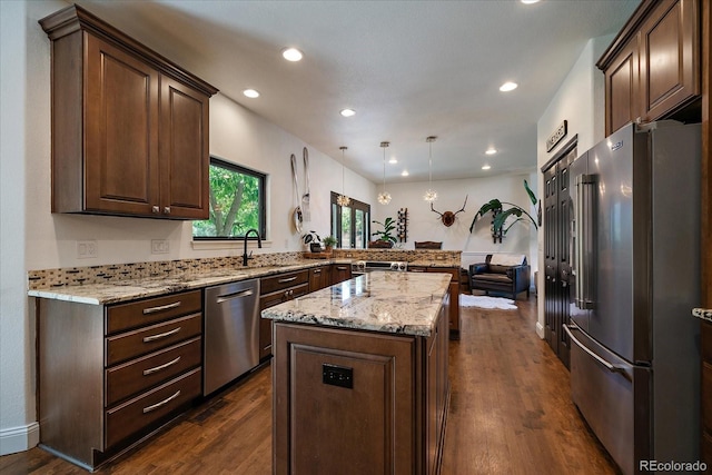 10701 Flagler Dr, Parker, CO 80134 - kitchen featuring appliances with stainless steel finishes, a center island, a peninsula, light stone counters, and dark wood-style flooring