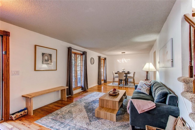 living room with a textured ceiling, light wood-type flooring, and baseboards