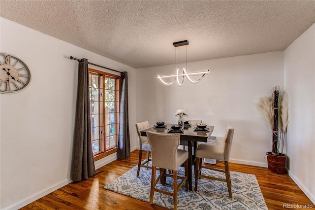 dining room with baseboards, a textured ceiling, an inviting chandelier, and wood finished floors