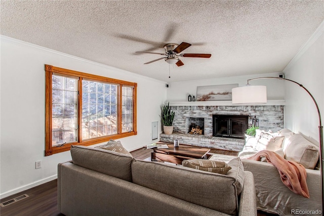 living area with visible vents, a ceiling fan, ornamental molding, a brick fireplace, and dark wood-style floors