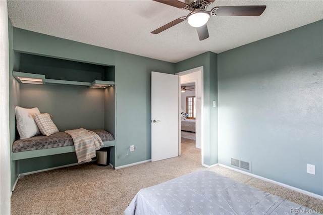 bedroom featuring a textured ceiling, a ceiling fan, visible vents, baseboards, and carpet