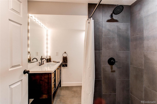 bathroom with tile patterned floors, baseboards, a tile shower, and vanity