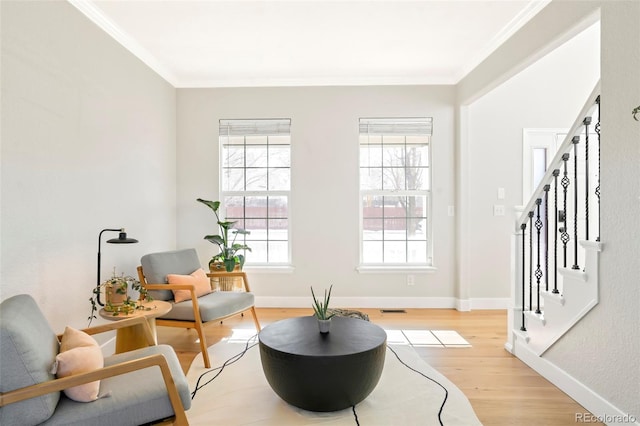 living area featuring ornamental molding, a healthy amount of sunlight, and light wood-type flooring