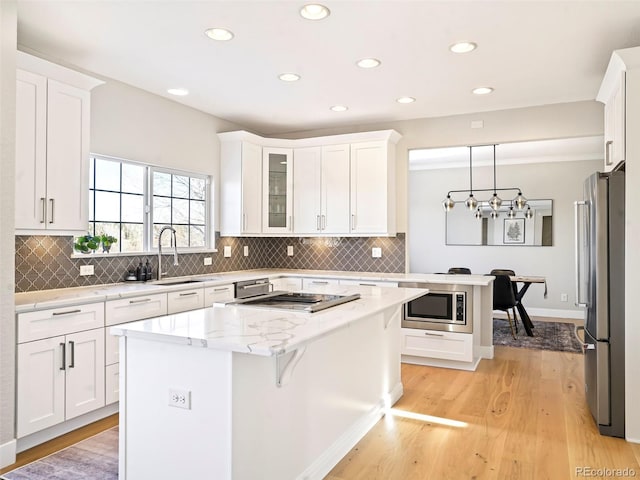 kitchen with pendant lighting, sink, white cabinets, and appliances with stainless steel finishes