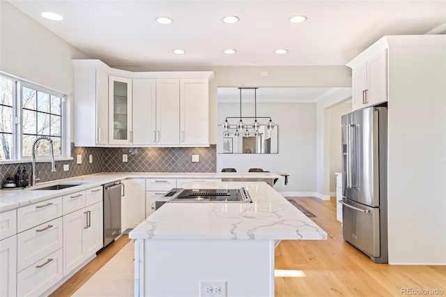 kitchen featuring sink, white cabinetry, a center island, appliances with stainless steel finishes, and pendant lighting