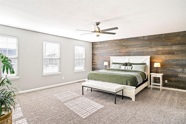 bedroom with carpet flooring, a textured ceiling, ceiling fan, and wood walls