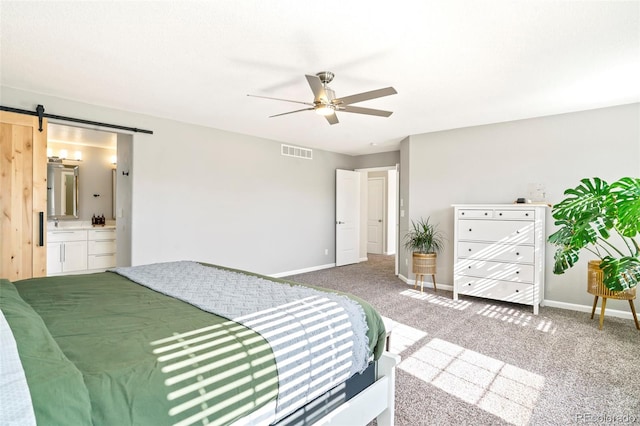 carpeted bedroom featuring ceiling fan, connected bathroom, and a barn door