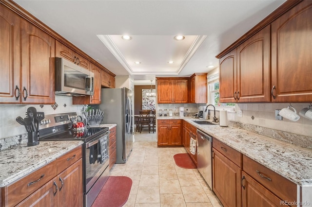 9926 W Nova Pl, Littleton, CO 80127 - kitchen featuring appliances with stainless steel finishes, a raised ceiling, decorative backsplash, brown cabinets, and light stone counters