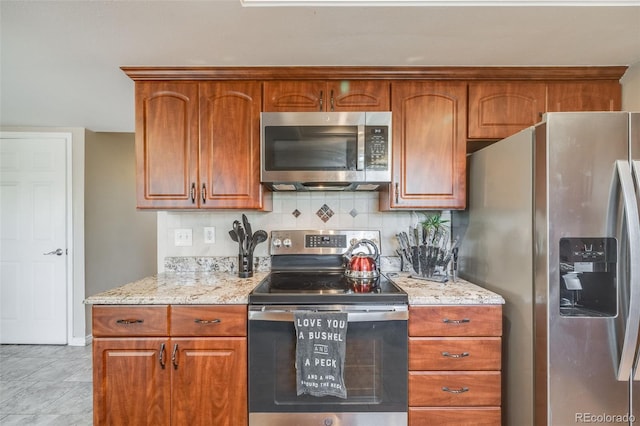 9926 W Nova Pl, Littleton, CO 80127 - kitchen featuring appliances with stainless steel finishes, light stone counters, decorative backsplash, and brown cabinetry
