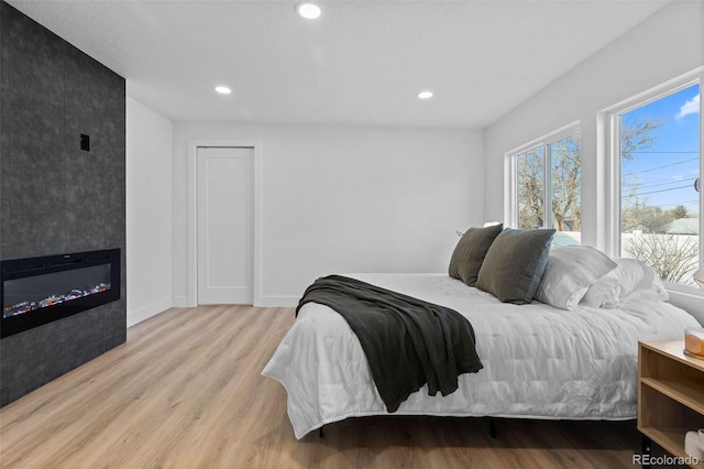 bedroom with a large fireplace and light wood-type flooring