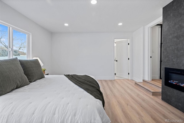 bedroom with a large fireplace and light hardwood / wood-style flooring