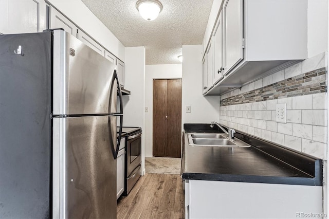 kitchen featuring wood-type flooring, sink, white cabinets, decorative backsplash, and stainless steel appliances