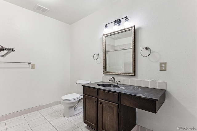 bathroom featuring a shower with door, vanity, tile patterned floors, and toilet