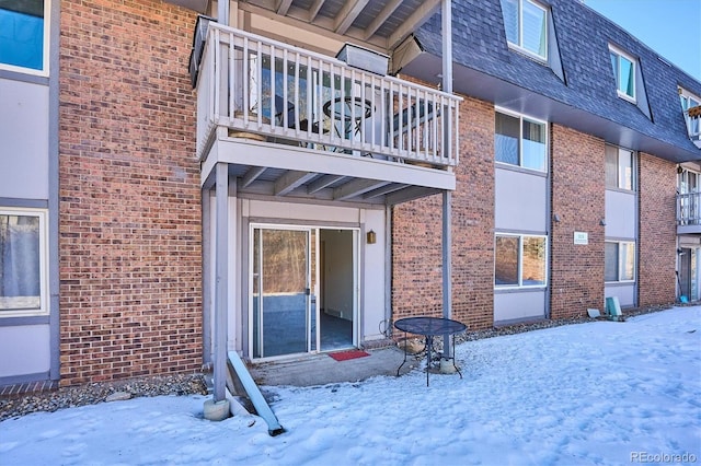 snow covered property entrance featuring a balcony