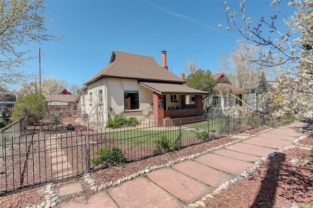view of front of property with roof with shingles, stucco siding, a chimney, and a fenced front yard