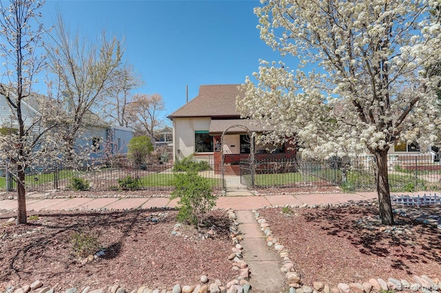 view of front of property featuring a fenced front yard, stucco siding, brick siding, and roof with shingles