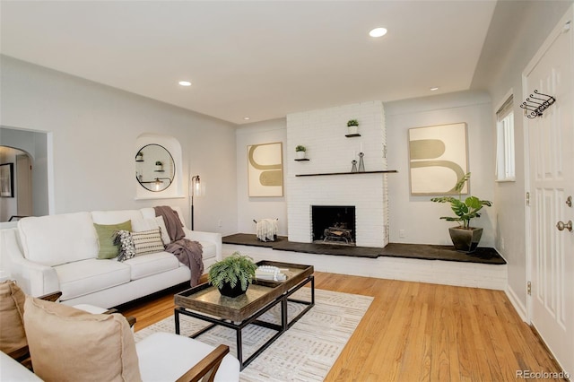 living room featuring recessed lighting, arched walkways, wood finished floors, and a fireplace