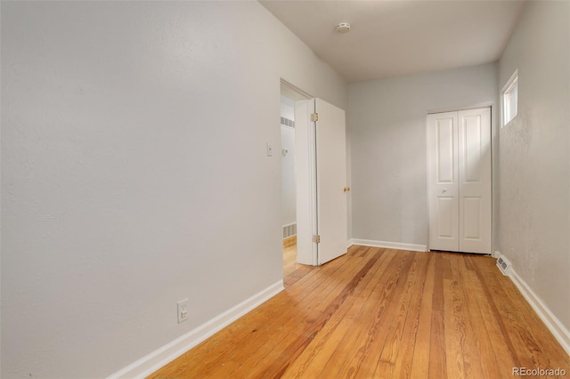 unfurnished bedroom with a closet, light wood-style floors, baseboards, and visible vents