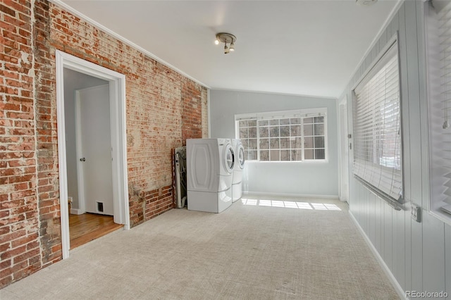 interior space with ornamental molding, vaulted ceiling, washer and dryer, brick wall, and baseboards