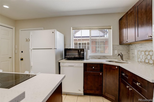 kitchen featuring light tile patterned floors, light countertops, black appliances, decorative backsplash, and a sink
