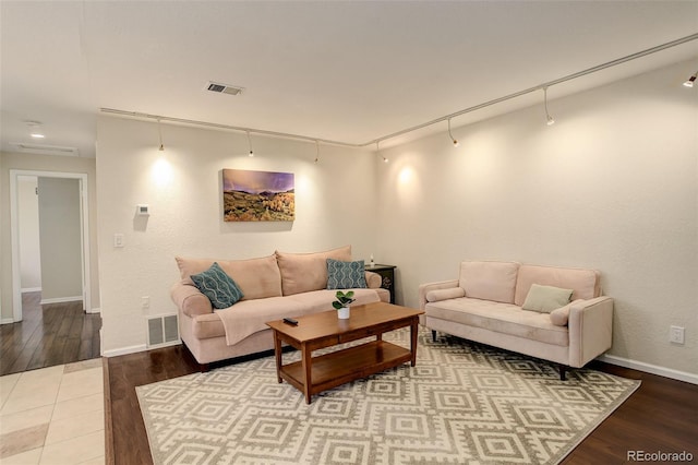 living room with track lighting, wood finished floors, and visible vents