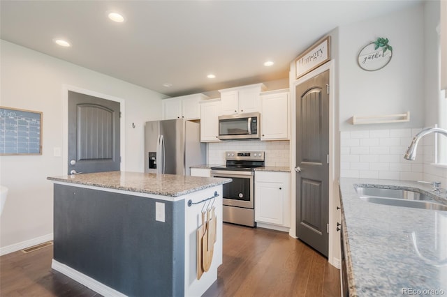 kitchen with white cabinets, stainless steel appliances, dark wood-type flooring, and a center island