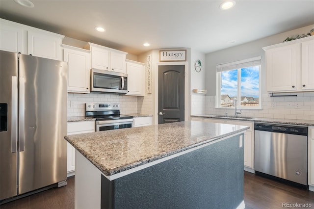 kitchen featuring appliances with stainless steel finishes, a kitchen island, dark wood-type flooring, and white cabinetry