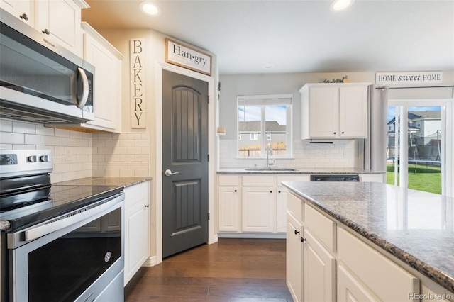 kitchen with sink, white cabinetry, stainless steel appliances, light stone countertops, and dark hardwood / wood-style flooring