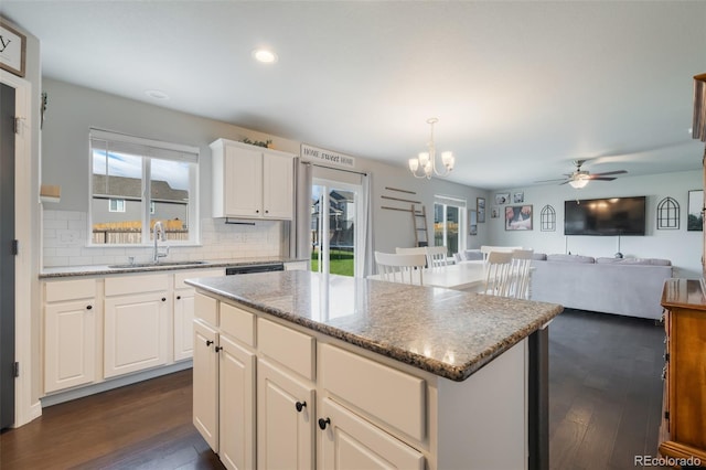 kitchen with a center island, dark hardwood / wood-style floors, sink, ceiling fan with notable chandelier, and hanging light fixtures