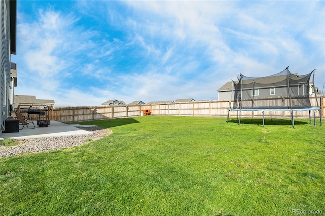 view of yard with a trampoline and a patio area