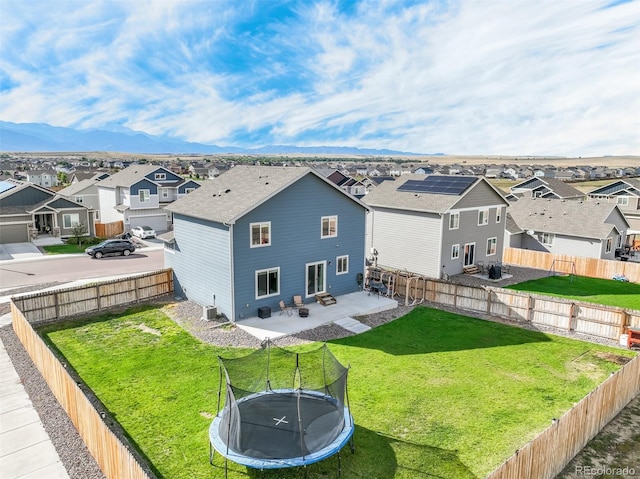 exterior space with a mountain view, a trampoline, central AC unit, a patio area, and a lawn