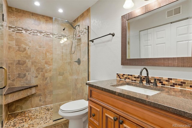 bathroom with an enclosed shower, vanity, tasteful backsplash, and toilet