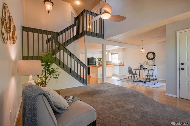 living room featuring ceiling fan, high vaulted ceiling, a textured ceiling, and hardwood / wood-style floors