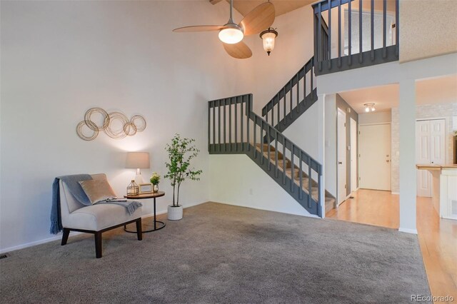 sitting room featuring ceiling fan, carpet flooring, and a high ceiling