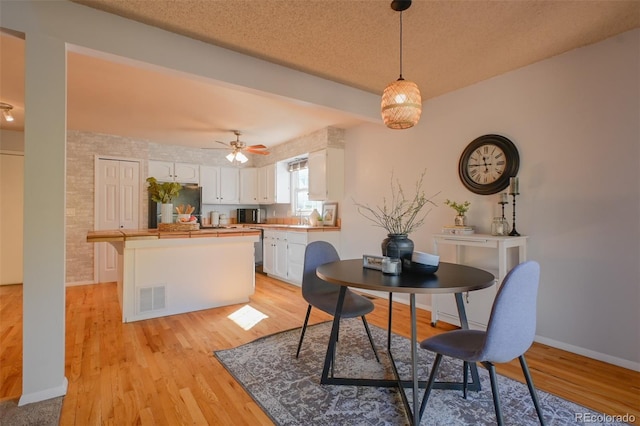 dining room featuring light hardwood / wood-style flooring, a textured ceiling, sink, and ceiling fan